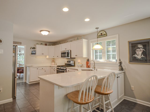 138 Page Rd, New London, NH 03257 - kitchen with stainless steel appliances, a peninsula, a kitchen bar, white cabinetry, and dark tile patterned floors