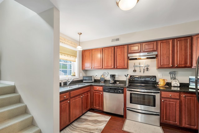 30 Brady Way Unit 5, Laconia, NH 03246 - kitchen with stainless steel appliances, under cabinet range hood, dark wood finished floors, hanging light fixtures, and dark stone countertops