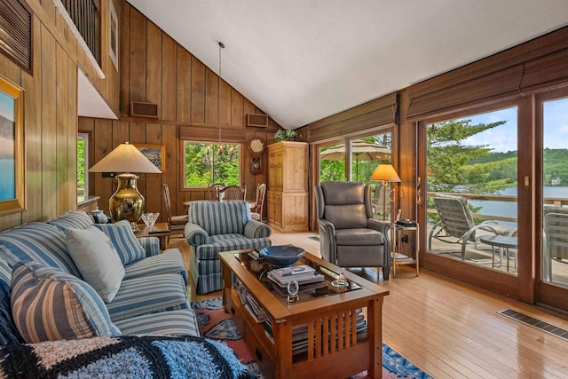 98 Marys Rd, Sunapee, NH 03782 - living area featuring healthy amount of natural light, high vaulted ceiling, wooden walls, light wood-style floors, and a water view