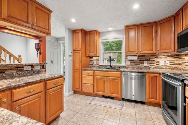 56 Durham Rd Unit 62, Dover, NH 03820 - kitchen featuring stainless steel appliances, backsplash, brown cabinets, a textured ceiling, and recessed lighting