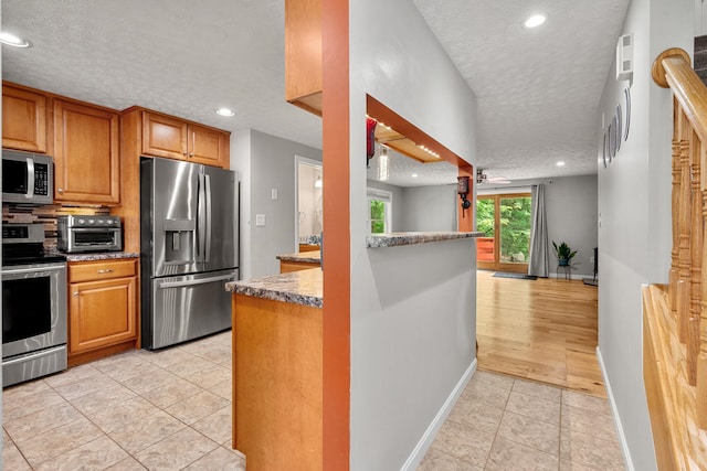 56 Durham Rd Unit 62, Dover, NH 03820 - kitchen with stainless steel appliances, a textured ceiling, light tile patterned floors, brown cabinets, and recessed lighting