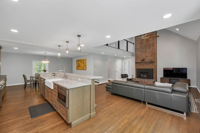 292 Forest Rd, Wolfeboro, NH 03894 - kitchen with stainless steel appliances, wood finished floors, a kitchen island with sink, light stone counters, and hanging light fixtures
