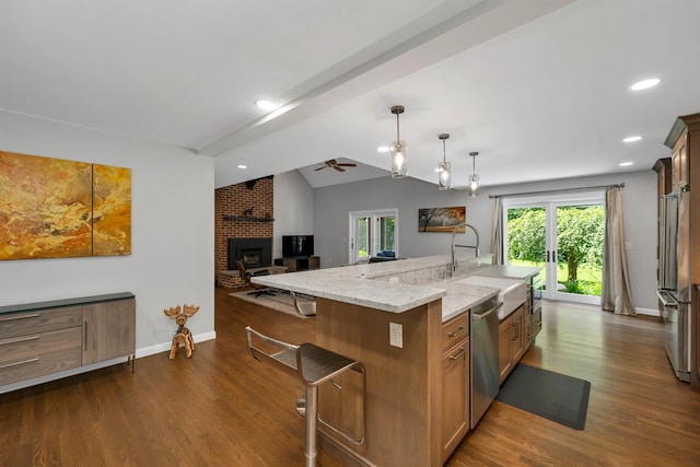 292 Forest Rd, Wolfeboro, NH 03894 - kitchen with stainless steel appliances, a fireplace, ceiling fan, light stone counters, and dark wood-type flooring