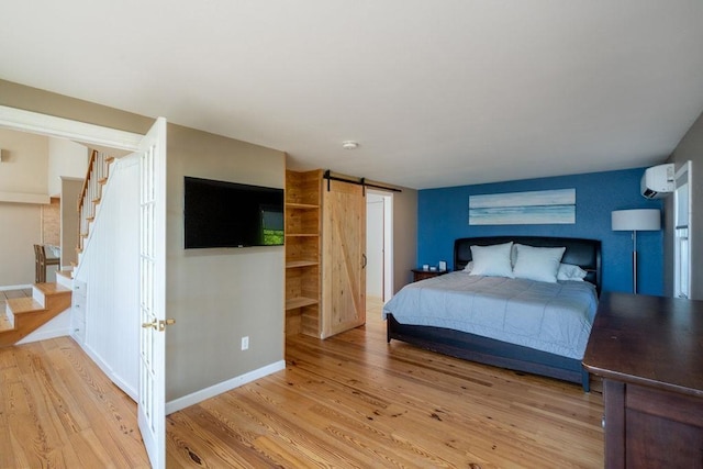 27 Wentworth Ter, Dover, NH 03820 - bedroom with a barn door, a wall mounted AC, and light wood-style flooring