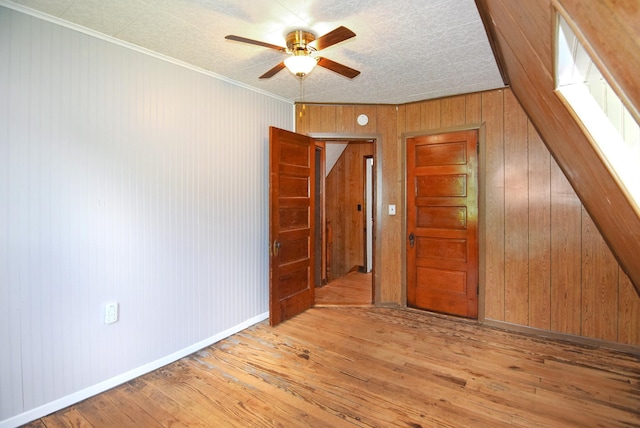 49 Bowker St, Claremont, NH 03743 - spare room featuring hardwood / wood-style flooring, wooden walls, a ceiling fan, and crown molding