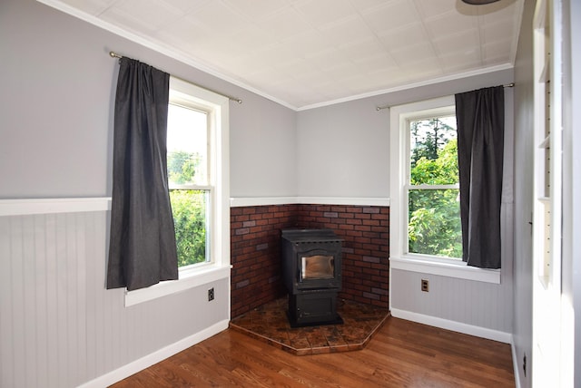 49 Bowker St, Claremont, NH 03743 - unfurnished living room featuring a wood stove, wood finished floors, ornamental molding, and wainscoting