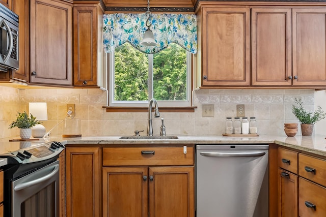 5 Cowin Rd, Merrimack, NH 03054 - kitchen featuring appliances with stainless steel finishes, brown cabinets, decorative backsplash, light stone countertops, and hanging light fixtures