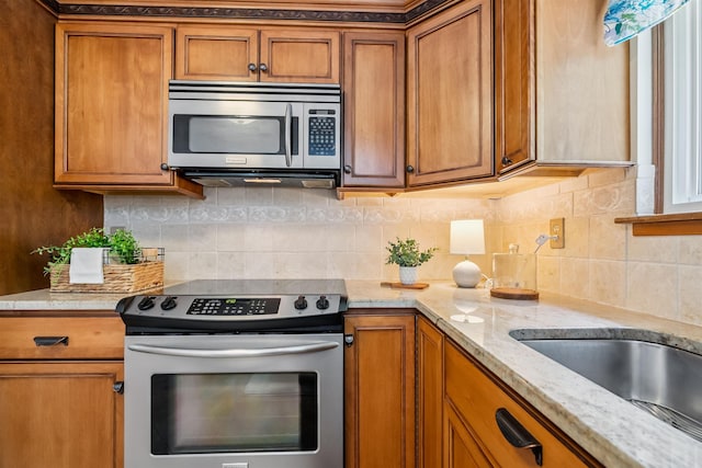5 Cowin Rd, Merrimack, NH 03054 - kitchen featuring appliances with stainless steel finishes, brown cabinets, light stone countertops, and decorative backsplash