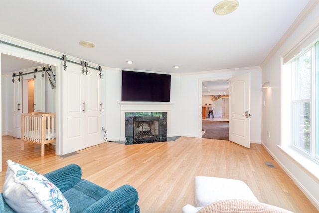 123 Stephen Dr, Goffstown, NH 03045 - living room featuring wood finished floors, a fireplace, healthy amount of natural light, a barn door, and ornamental molding