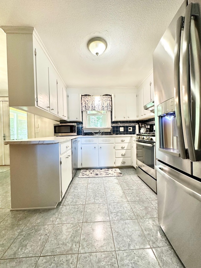 22 Mason Rd, Merrimack, NH 03054 - kitchen with stainless steel appliances, a textured ceiling, white cabinetry, under cabinet range hood, and tasteful backsplash