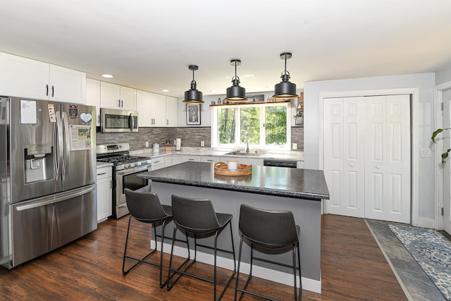 2129 E Conway Rd, Conway, NH 03813 - kitchen with appliances with stainless steel finishes, a kitchen breakfast bar, dark wood-style floors, backsplash, and white cabinets