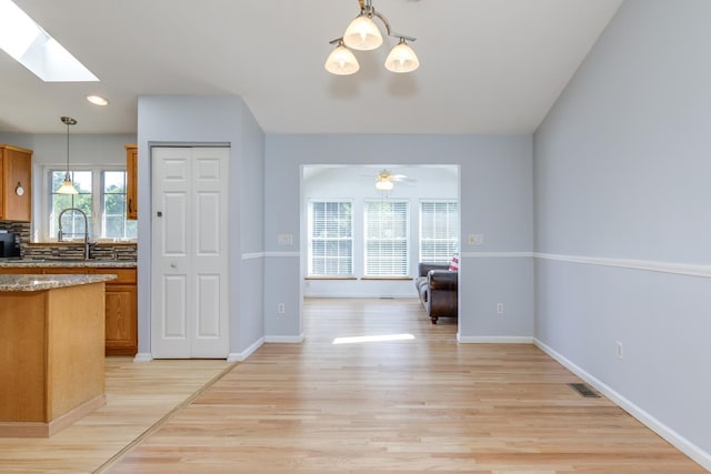 4 Lancer Ln, Danville, NH 03819 - kitchen featuring brown cabinets, light wood finished floors, a skylight, hanging light fixtures, and light stone countertops