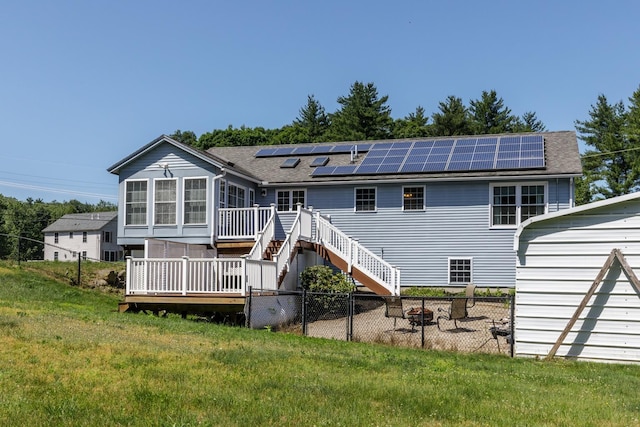 4 Lancer Ln, Danville, NH 03819 - back of property featuring a wooden deck, roof mounted solar panels, a shingled roof, and a fenced backyard