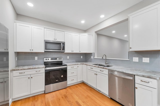 8C Villa Ln, Goffstown, NH 03045 - kitchen with stainless steel appliances, white cabinets, light wood finished floors, decorative backsplash, and recessed lighting