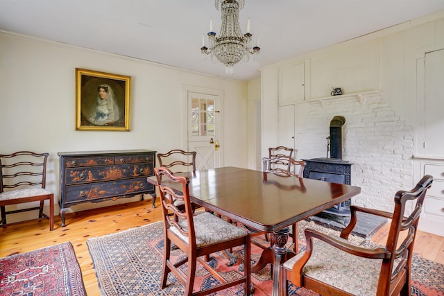 102 Hubbard Hill Rd, Rindge, NH 03461 - dining space featuring light wood finished floors, a chandelier, a wood stove, and ornamental molding