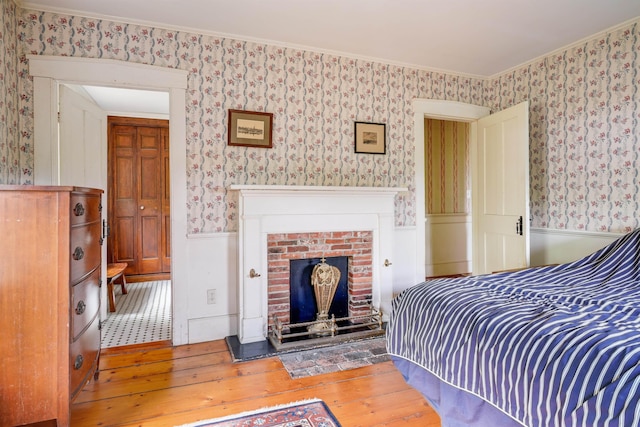 102 Hubbard Hill Rd, Rindge, NH 03461 - bedroom featuring wallpapered walls, hardwood / wood-style floors, wainscoting, a brick fireplace, and a closet