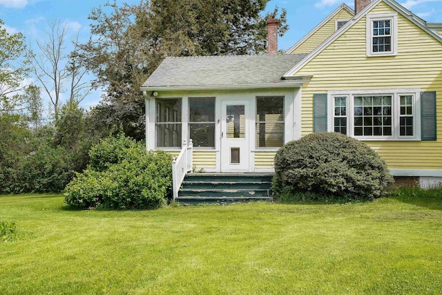 102 Hubbard Hill Rd, Rindge, NH 03461 - view of front facade with a chimney, a front yard, a shingled roof, and a sunroom