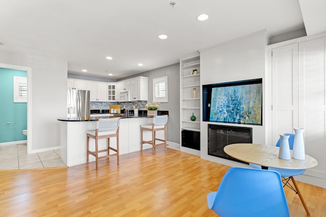 520 Ocean Blvd Unit 10, Hampton, NH 03842 - kitchen with stainless steel fridge with ice dispenser, white microwave, light wood-style floors, a kitchen breakfast bar, and glass insert cabinets