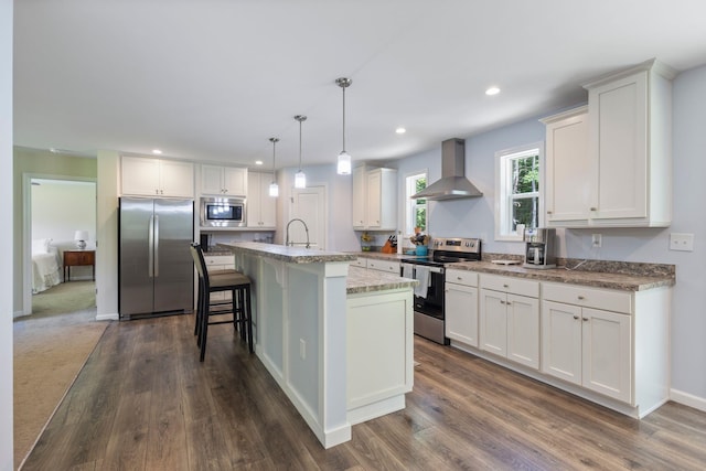 23 Pork Hill Rd, Ossipee, NH 03864 - kitchen featuring appliances with stainless steel finishes, wall chimney range hood, white cabinets, recessed lighting, and an island with sink