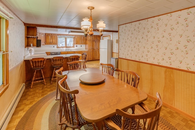 141 Manns Hill Rd, Littleton, NH 03561 - dining area with baseboard heating, a wainscoted wall, a chandelier, wood walls, and wallpapered walls