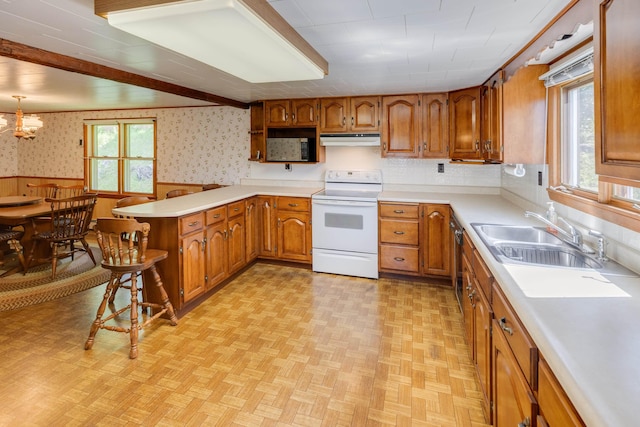 141 Manns Hill Rd, Littleton, NH 03561 - kitchen featuring white electric stove, under cabinet range hood, wallpapered walls, brown cabinets, and a peninsula