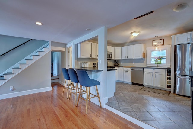 15 Arbor St # 1, Exeter, NH 03833 - kitchen with appliances with stainless steel finishes, a kitchen bar, a peninsula, white cabinets, and dark countertops