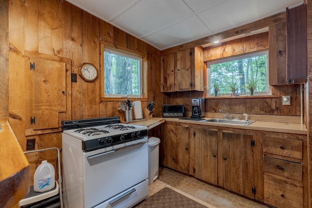 396 Mica Point Rd, Barrington, NH 03825 - kitchen featuring white gas range oven, healthy amount of natural light, brown cabinets, and wooden walls