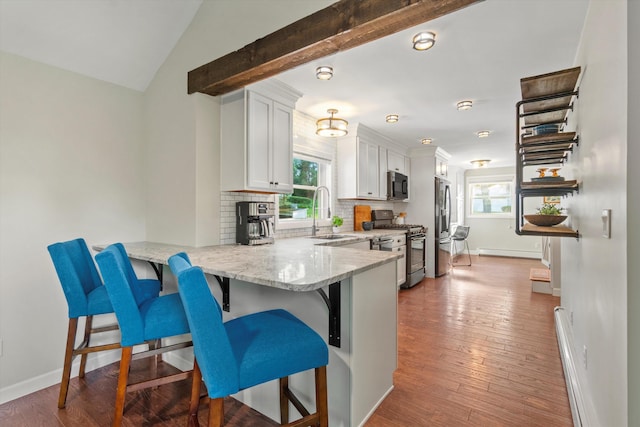 38 Heald St, Goffstown, NH 03102 - kitchen featuring appliances with stainless steel finishes, a kitchen breakfast bar, decorative backsplash, white cabinetry, and a peninsula