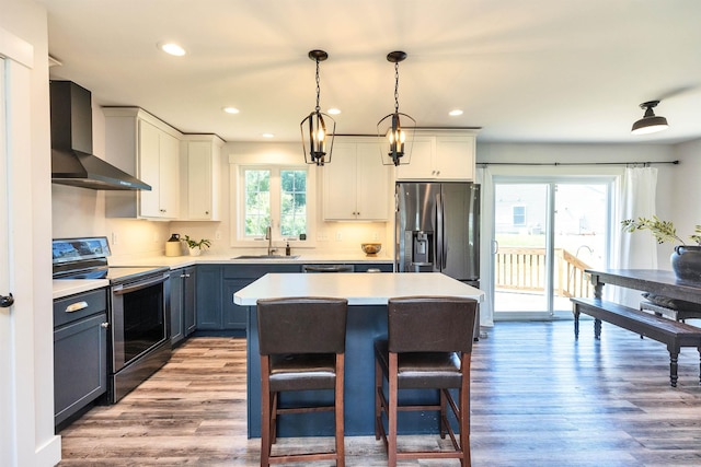 39 Windy Fields Ln, Jaffrey, NH 03452 - kitchen featuring wall chimney range hood, appliances with stainless steel finishes, wood finished floors, a kitchen island, and light countertops