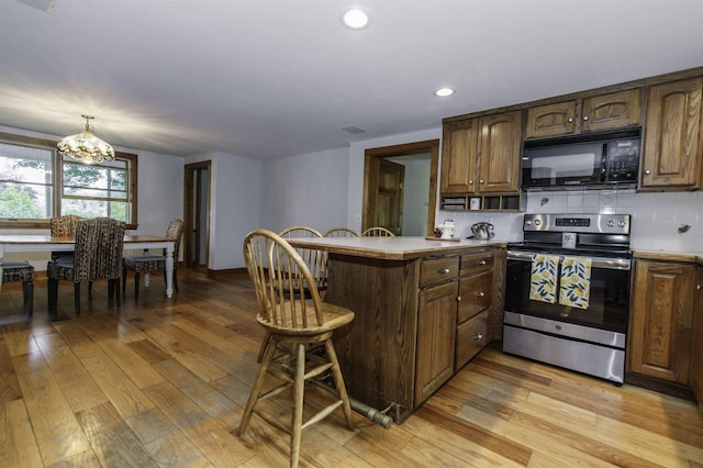 153 N Rd, Brentwood, NH 03833 - kitchen featuring black microwave, electric stove, a peninsula, a breakfast bar area, and light wood finished floors