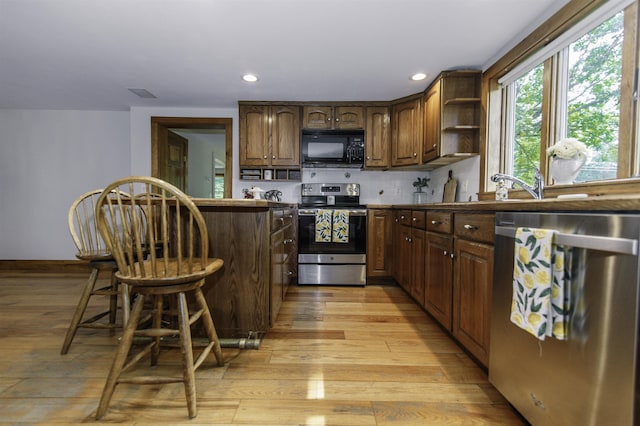 153 N Rd, Brentwood, NH 03833 - kitchen with stainless steel appliances, light wood-type flooring, open shelves, a breakfast bar area, and tasteful backsplash