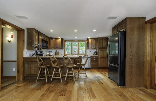 153 N Rd, Brentwood, NH 03833 - kitchen with black appliances, light wood finished floors, a peninsula, a kitchen bar, and recessed lighting