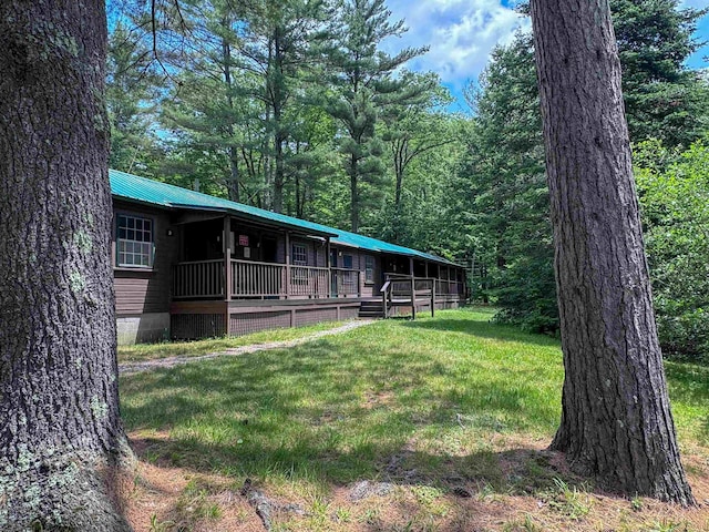1043 Main St, Sunapee, NH 03751 - view of front of house with a front yard, a metal roof, and a view of trees
