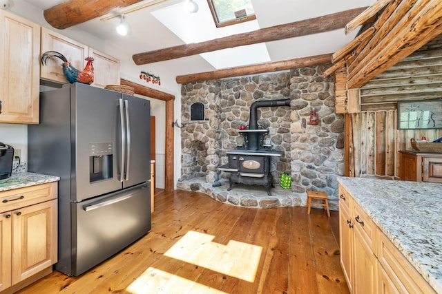 83 Towle Rd, Jackson, NH 03846 - kitchen featuring stainless steel fridge, light brown cabinets, beam ceiling, a wood stove, and light wood-style flooring