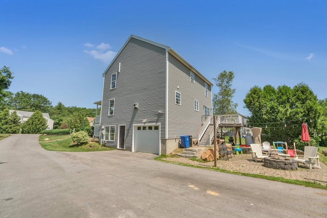 15 Winslow Dr, Somersworth, NH 03878 - view of side of home featuring a fire pit, stairway, an attached garage, a wooden deck, and driveway
