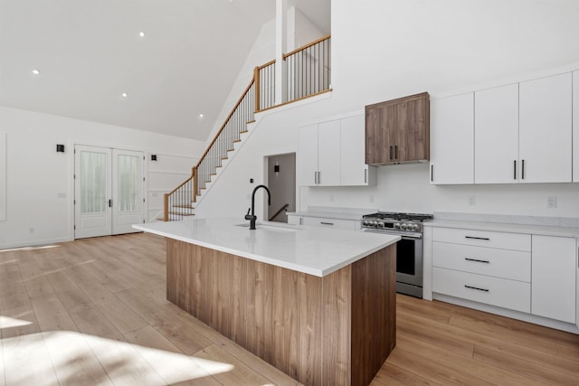 74 Scenic View Rd, Ashland, NH 03217 - kitchen with stainless steel gas stove, high vaulted ceiling, light wood-type flooring, white cabinets, and light countertops