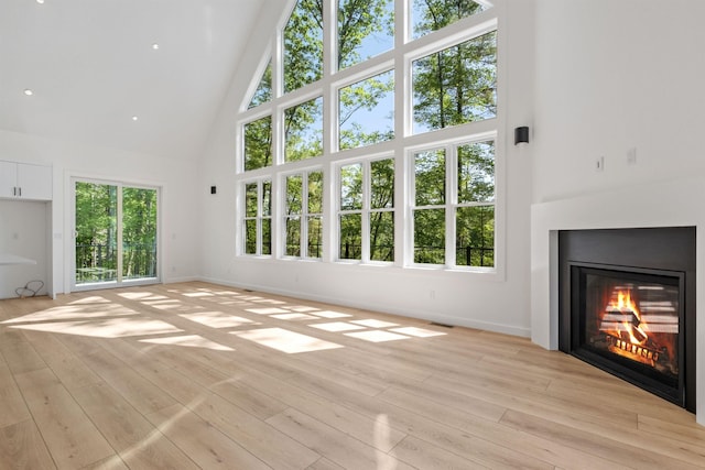 74 Scenic View Rd, Ashland, NH 03217 - unfurnished living room featuring high vaulted ceiling, a glass covered fireplace, and light wood-style flooring