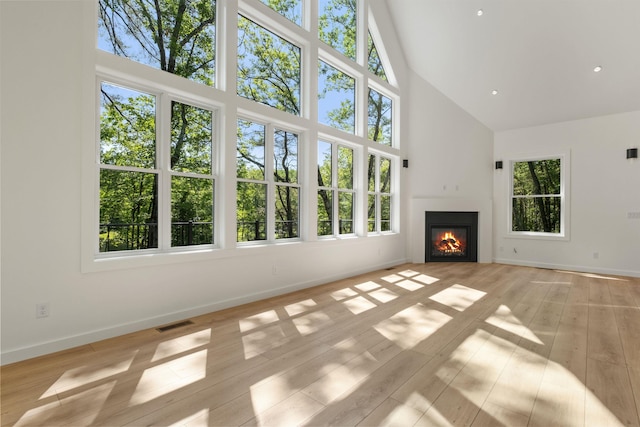 74 Scenic View Rd, Ashland, NH 03217 - unfurnished living room with high vaulted ceiling, plenty of natural light, light wood-style floors, and a glass covered fireplace