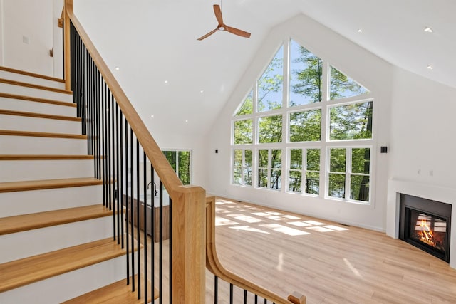 74 Scenic View Rd, Ashland, NH 03217 - stairway featuring healthy amount of natural light, ceiling fan, high vaulted ceiling, wood finished floors, and a glass covered fireplace