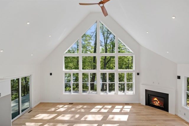 74 Scenic View Rd, Ashland, NH 03217 - unfurnished living room with high vaulted ceiling, ceiling fan, a glass covered fireplace, plenty of natural light, and light wood finished floors