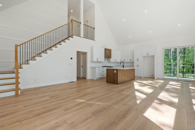 74 Scenic View Rd, Ashland, NH 03217 - unfurnished living room featuring high vaulted ceiling, light wood-style floors, and stairway