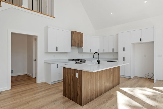 74 Scenic View Rd, Ashland, NH 03217 - kitchen with high vaulted ceiling, light wood-type flooring, light countertops, white cabinets, and a kitchen island with sink