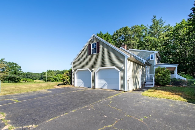 144 Packers Falls Rd, Durham, NH 03824 - view of side of property with asphalt driveway, a chimney, and a garage