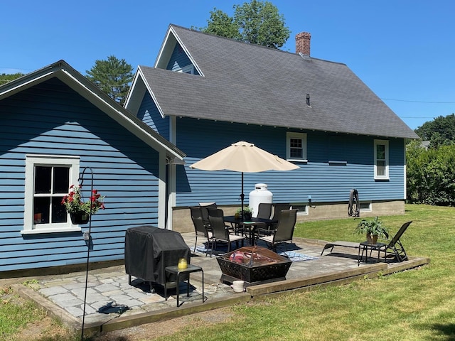 34 Dewey St, Springfield, VT 05156 - back of property featuring a fire pit, a yard, a patio, a shingled roof, and a chimney