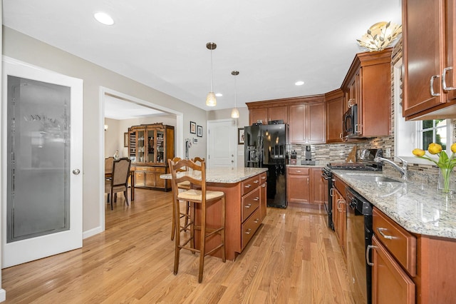 4 Chestnut St, Hudson, NH 03051 - kitchen featuring black appliances, a kitchen breakfast bar, light wood-style flooring, a center island, and tasteful backsplash