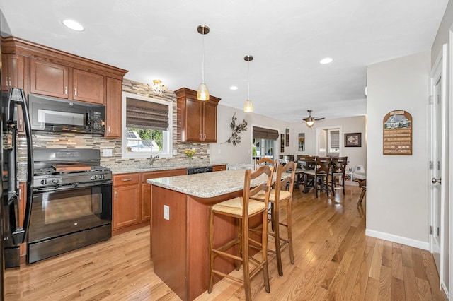 4 Chestnut St, Hudson, NH 03051 - kitchen with black appliances, decorative backsplash, brown cabinets, light wood-style floors, and a kitchen breakfast bar