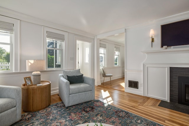 45 Atlantic Ave, North Hampton, NH 03862 - living area with a brick fireplace, light wood-type flooring, healthy amount of natural light, and ornamental molding