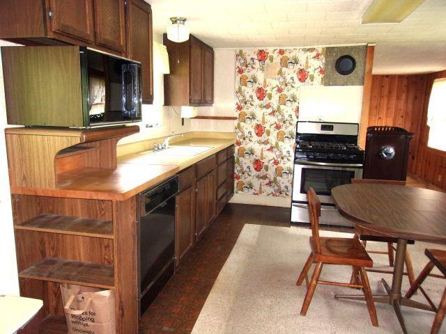 70 Wild Ammonoosuc Rd, Haverhill, NH 03785 - kitchen with black appliances, light countertops, wallpapered walls, and dark wood-style flooring