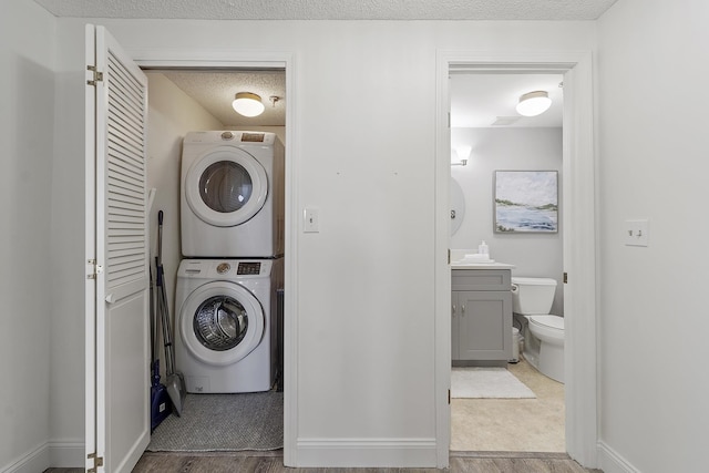 407 Ocean Blvd Unit A11, Hampton, NH 03842 - washroom featuring stacked washer / dryer, a textured ceiling, and wood finished floors