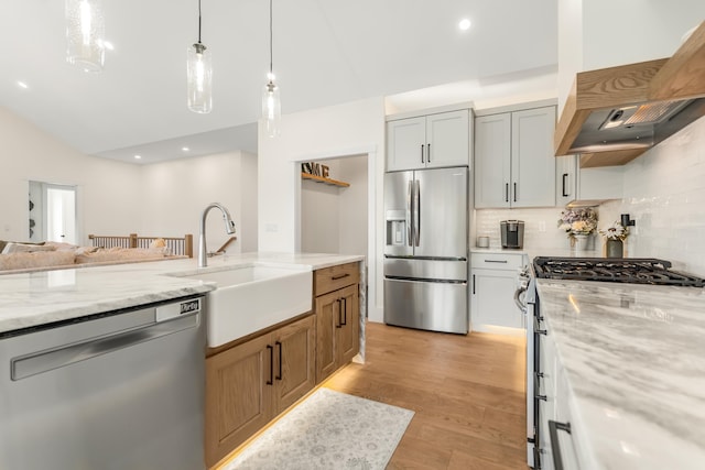422 Blane Cir Unit 50, Pembroke, NH 03275 - kitchen featuring stainless steel appliances, premium range hood, decorative backsplash, light stone counters, and light wood-style flooring